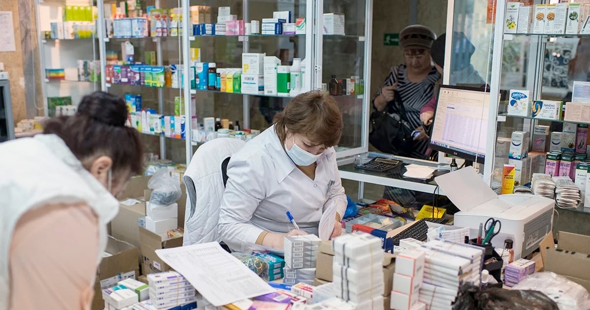 Mai multe farmaciste și cutii cu medicamente, într-o farmacie.