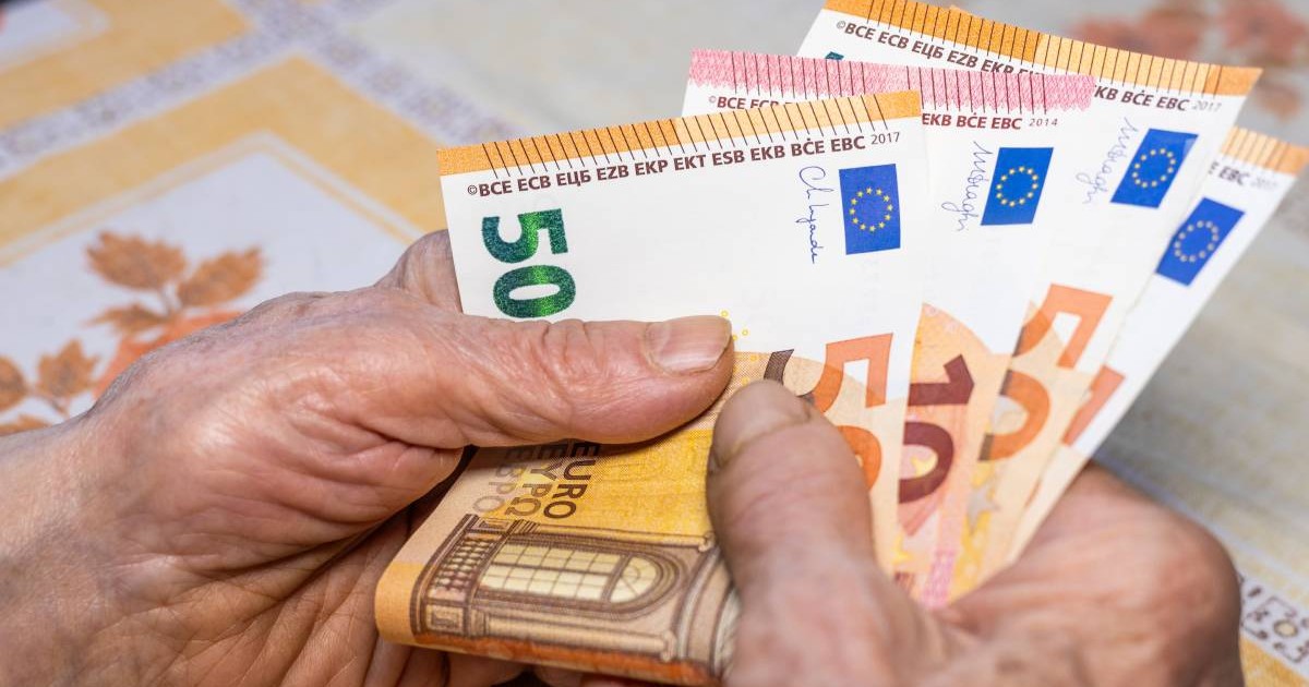 Pensionară care ține în mână mai multe bancnote de 50 și 10 euro