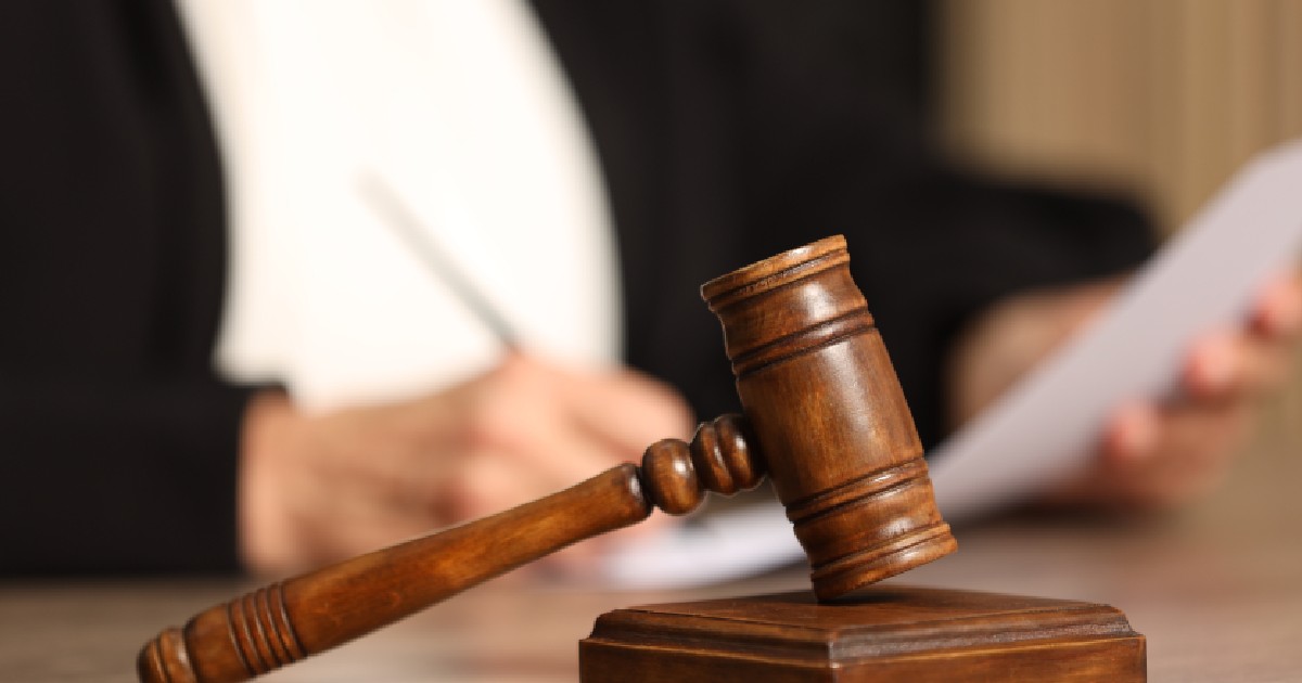 Un judecător se uită pe niște documente, iar în fața lui se află un „ciocan de justiție”