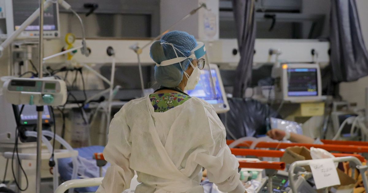 Un cadru medical cu mască de protecție trece pe lângă pacienții internați într-un salon la Spitalul Universitar de Urgență București