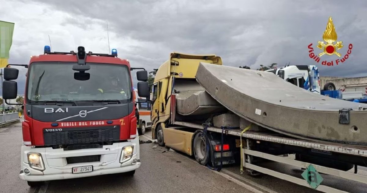 Imaginea arată un camion Volvo roșu de pompieri și un TIR încărcat cu un bloc de beton, după un accident pe autostradă