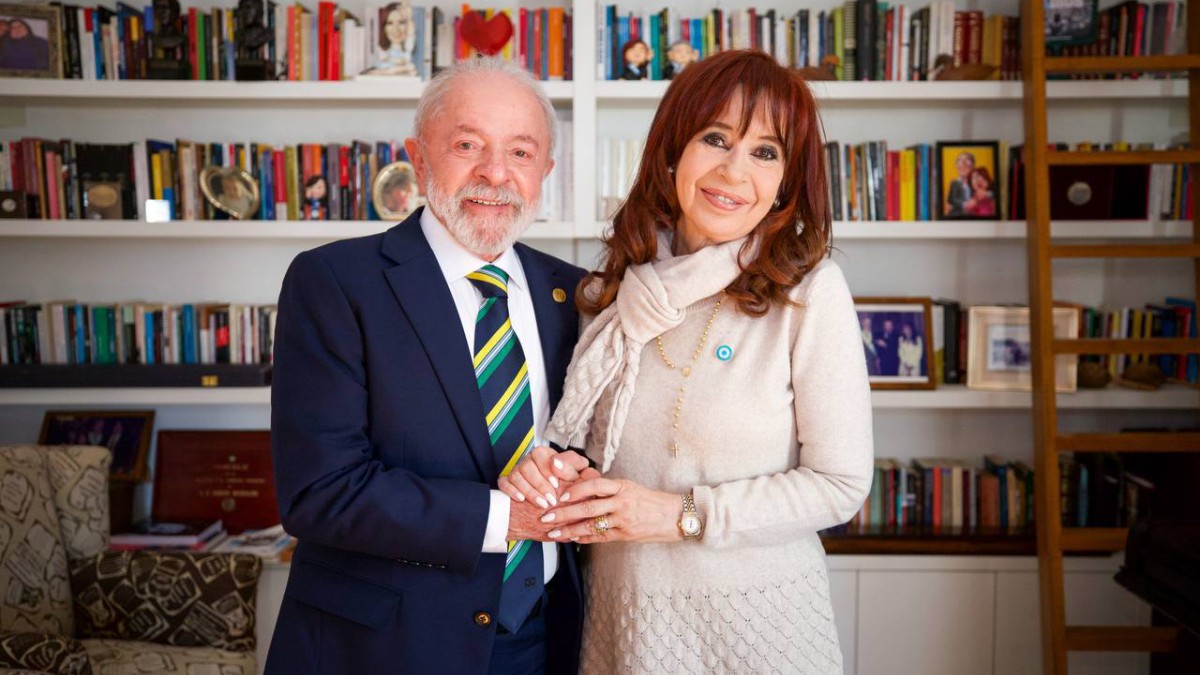 Luiz Inácio Lula da Silva și Cristina Kirchner, ea îmbrăcată într-o rochie crem și el îmbrăcat într-un costum bleumarin, cămașă albă și cravată în dungi. Pe fundal, o bibliotecă