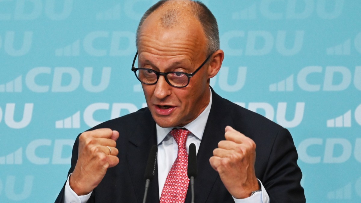 Cancelarul german Friedrich Merz vorbind gesticulând cu ambii pumni strânși în fața unui fundal cu sigla partidului CDU
