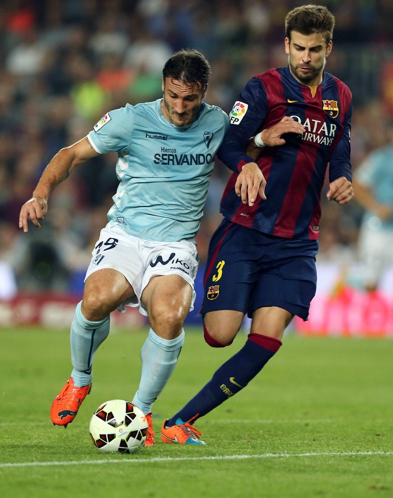epa04452906 FC Barcelona's defender Gerard Pique (R) fights for the ball with Federico Piovaccari (L), of Eibar, during their Spanish Primera Division soccer match played at Camp Nou stadium in Barcelona, northeastern Spain, on 18 October 2014. EPA/TONI ALBIR
