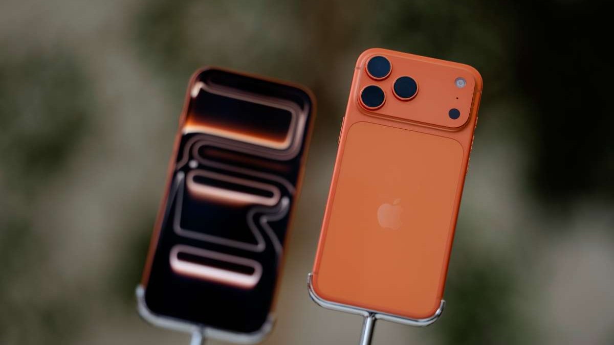 Două iPhone-uri 17 Pro, de culoare portocalie, unul cu fața, celălalt cu spatele, pe standuri de prezentare.