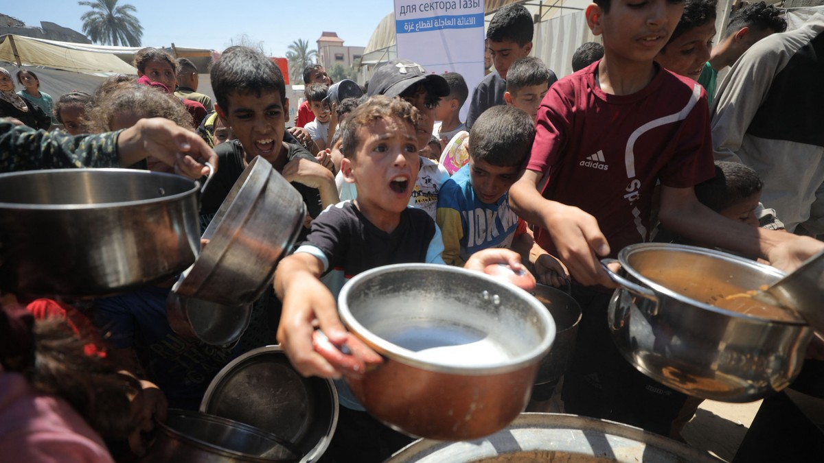 Un copil palestinian întinde oala în care vrea să primească ajutoare umanitare.