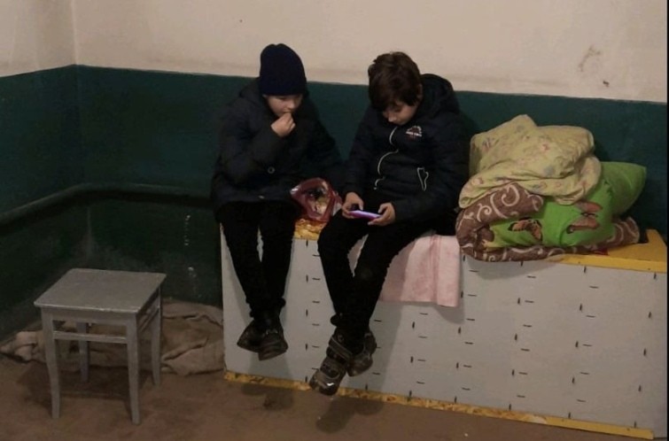 Maksim, stânga, jucându-se pe un telefon alături de un prieten, în adăpostul subteran din Cernihiv.