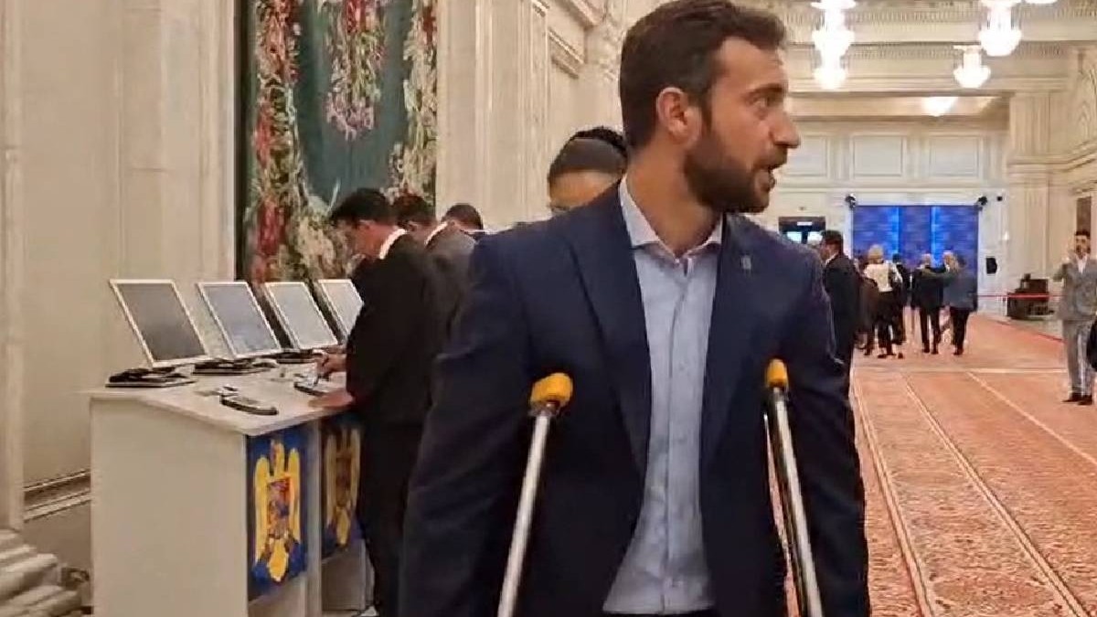 Parlamentarul AUR sosit în cârje în Parlament, îmbrăcat la costum.