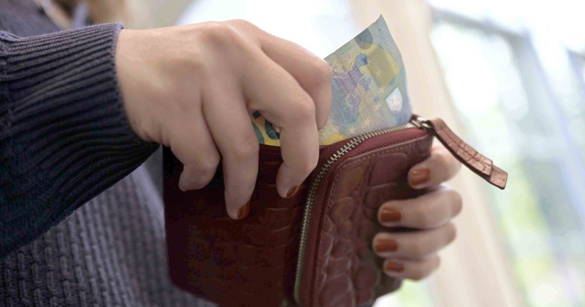 O femeie scoate o bancnotă de 20 de euro din portofel.