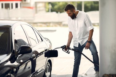 Handsome man pours gasoline into tank of car