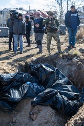Soldatul ucrainean încearcă să-și stăpânească lacrimile, în fața unei gropi comune, unde se află alături de jurnaliști | Foto: Profimedia