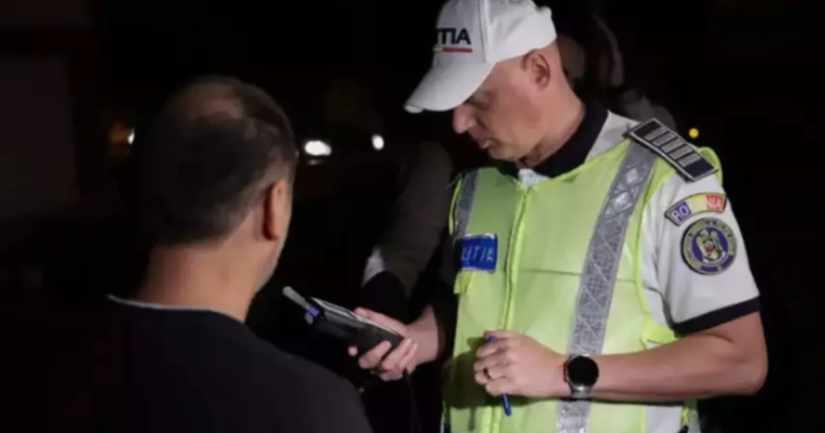 Un polițist care ține un alcooltest în mână, lângă un bărbat