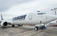 O aeronavă albă TAROM (cu numele de botez „Ivan Patzaichin” inscripționat în partea din față) staționată pe pista unui aeroport.