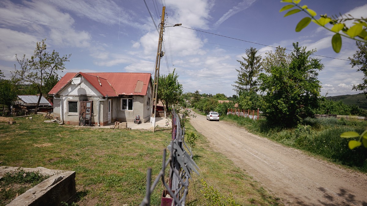 Imagine dintr-un sat, drumul cu o masina de politie si o casa