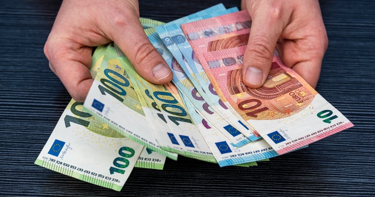 Un bărbat care ține bancnote de euro în mână.
