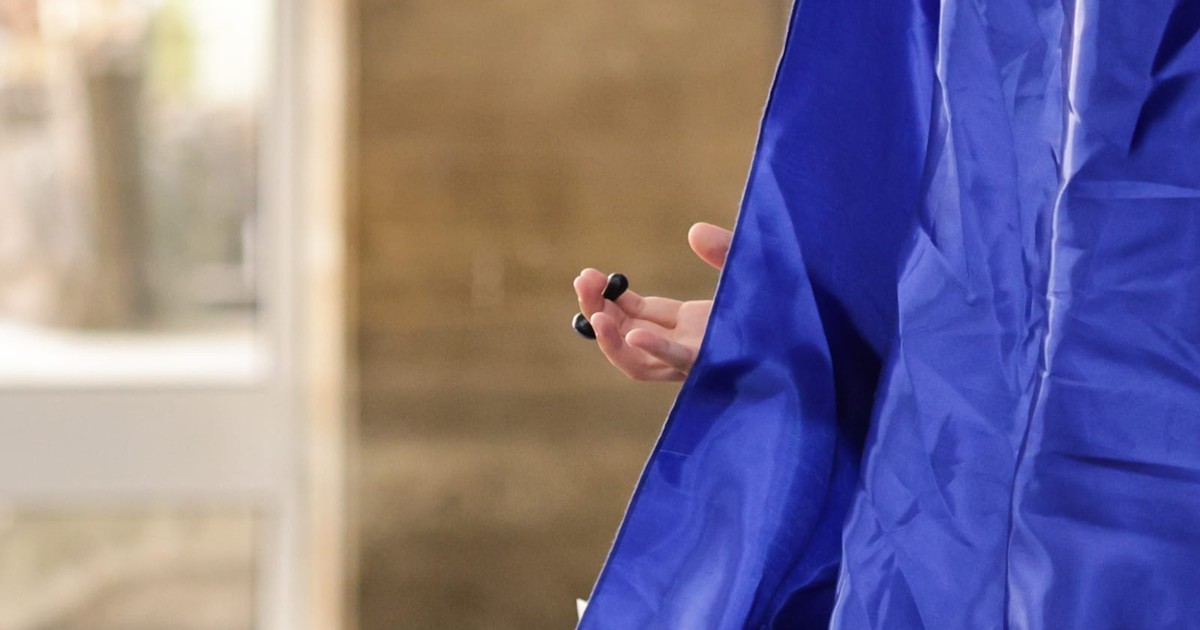 Poză cu o persoană aflată în cabina de vot, iar în poză i se vede doar o mână cu ștampila de vot