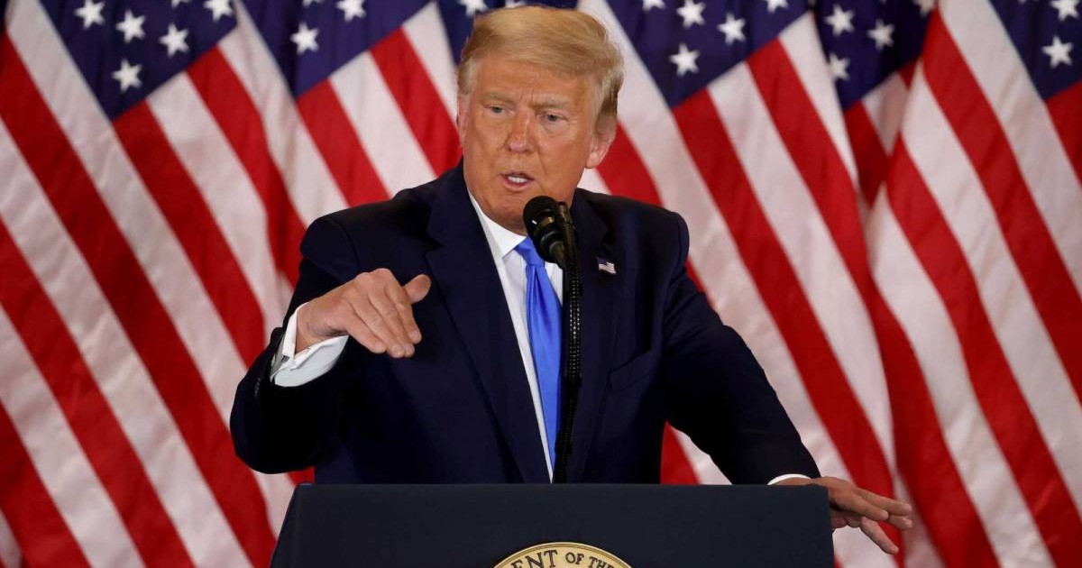 donald trump in timpul unui discurs, in spatele sau steagul americii