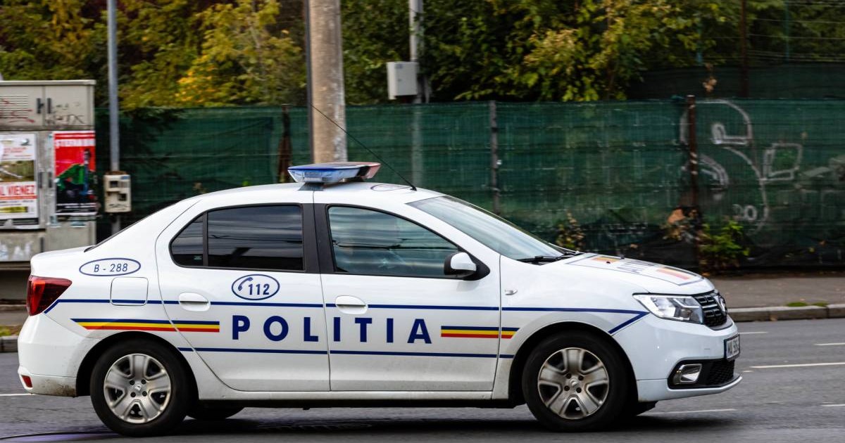 O mașină de Poliție inscripționată care circulă pe stradă în centrul orașului și se deplasează spre locul intervenției