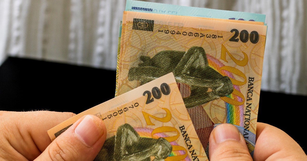 Un bărbat care numără banii cash, sunt hârtii de 200 și 100 de lei