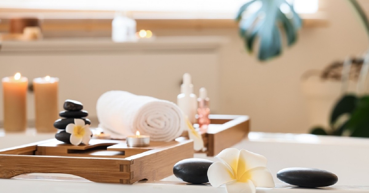 Spa-ul de acasă: obiectele mici care schimbă atmosfera - O baie transformata într-un spa cu o cadă albă decorată ca la spa cu lumânări, flori, roci vulcanice