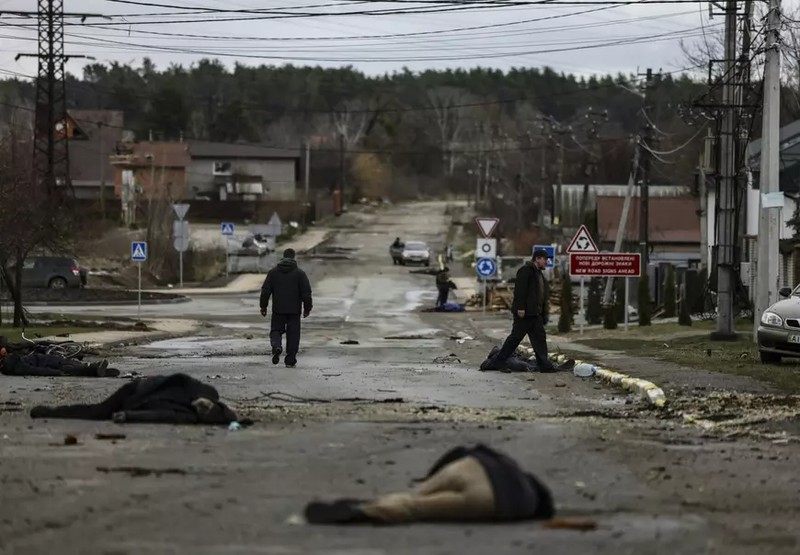 Un bărbat trece pe lângă trupurile neînsuflețite ale unor civili uciși pe o stradă din Bucha. 2 aprilie 2022. Foto: Profimedia
