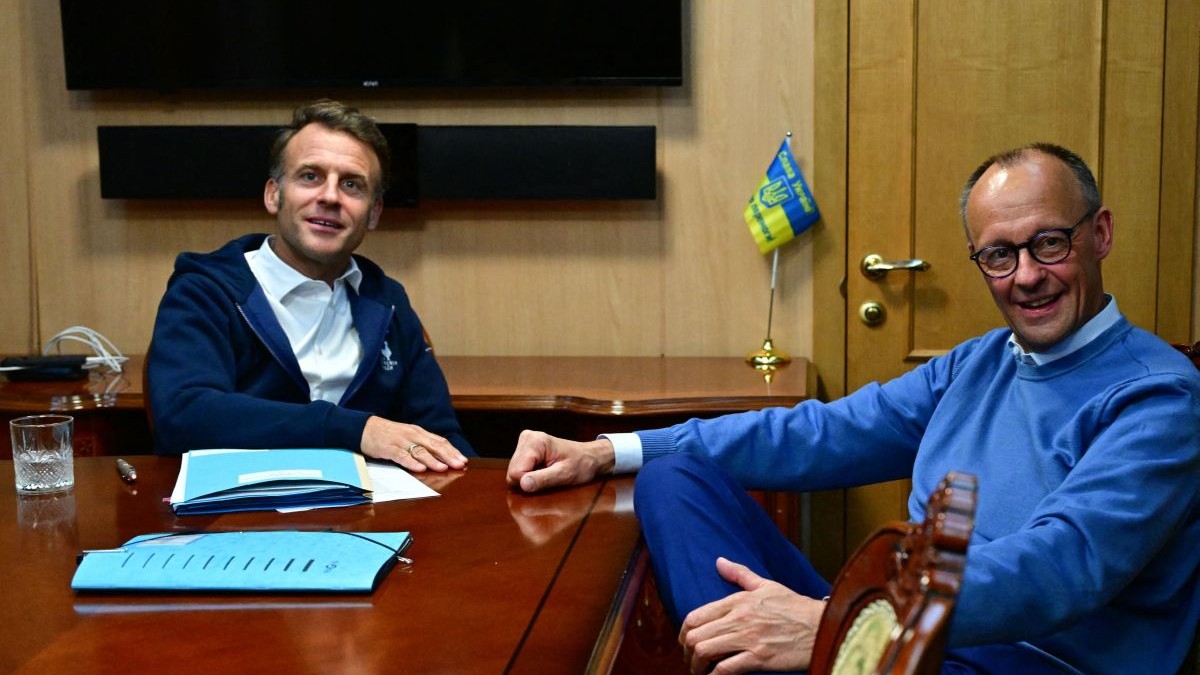 Emmanuel Macron și Friedrich Merz stau la masă în ținute sport la bordul unui tren care merge spre Kiev, mai 2025