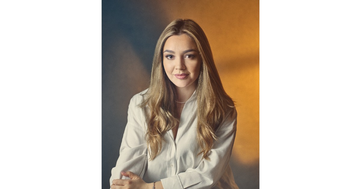 Fotografie portret cu Ilinca Simion in fata unui perete. Aceasta poarta o camasa alba