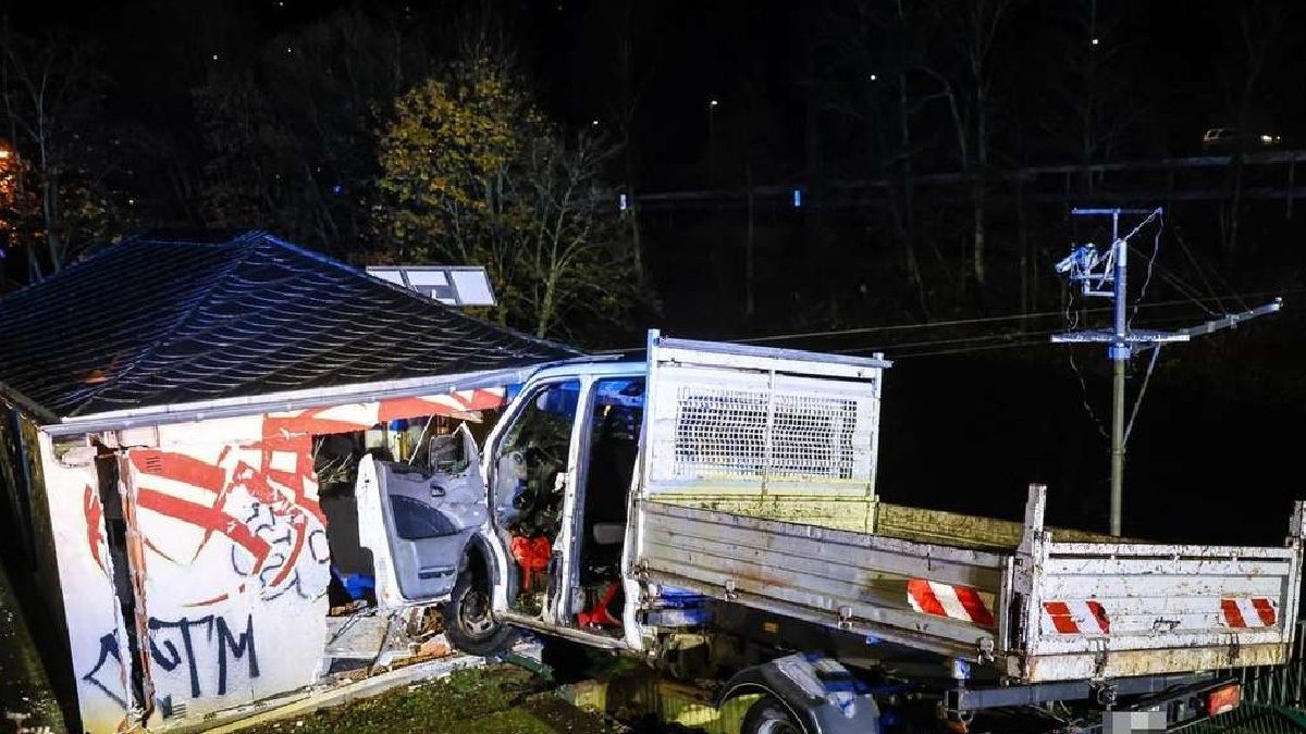 O fotografie nocturnă arată o autoutilitară albă care s-a izbit de construcție, lângă un lac.