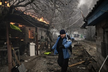 Un bărbat merge lângă o casă care arde după ce a fost bombardată în orașul Irpin, în afara Kiev, pe 4 martie 2022. Foto: Profimedia