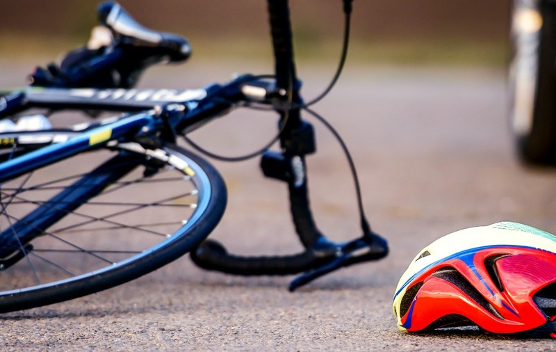 O bicicletă căzută pe jos. Lângă aceasta se află o caschetă colorată