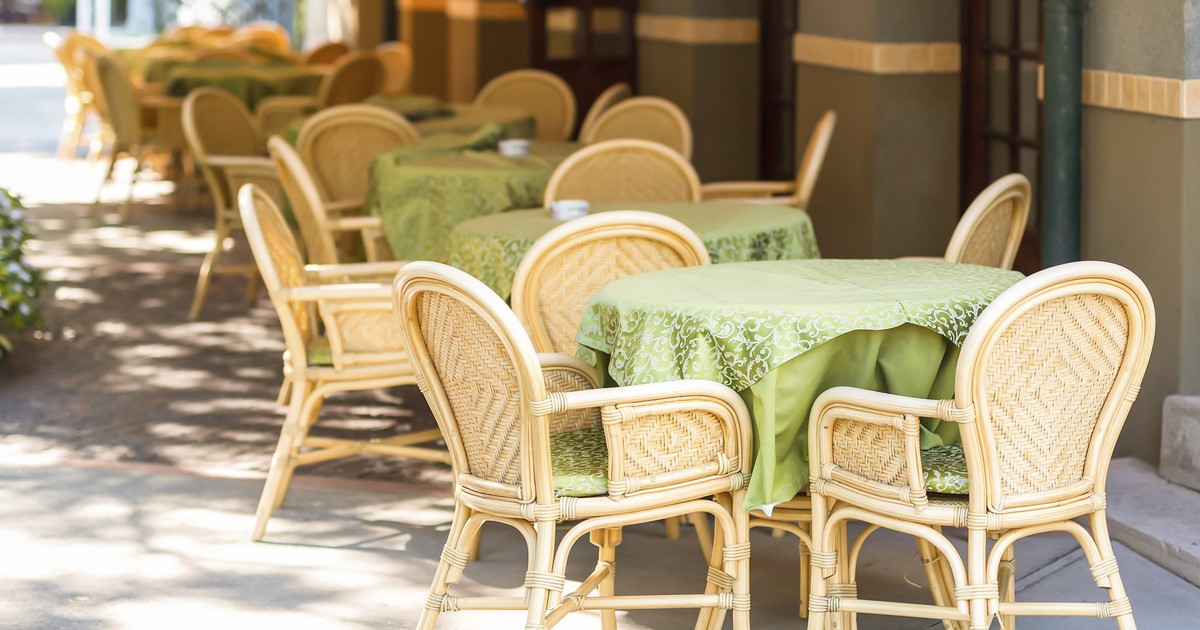 Imagine cu mai multe mese și scaune goale pe o terasă a unui restaurant.