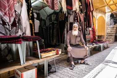 În așteptarea clienților, un vânzător stă în fața magazinului său de haine și accesorii vestimentare arăbești tradiționale