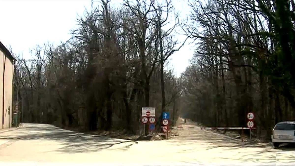 O răspântie de două drumuri la pădure, la cel din dreapta se vede o barieră pusă pe unde nu pot trece mașinile, iar un autoturism este parcat acolo