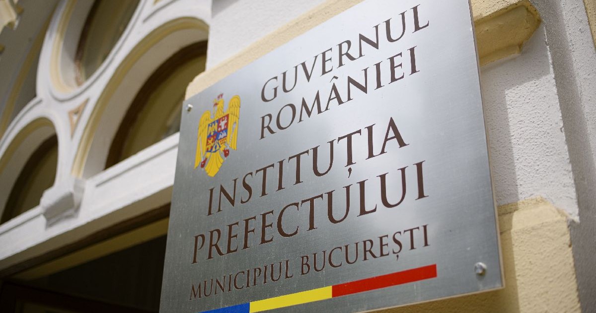 Imaginea prezintă o placă fixată pe peretele exterior al unei clădiri, pe care scrie „GUVERNUL ROMÂNIEI – INSTITUȚIA PREFECTULUI – MUNICIPIUL BUCUREȘTI”, lângă stema României.
