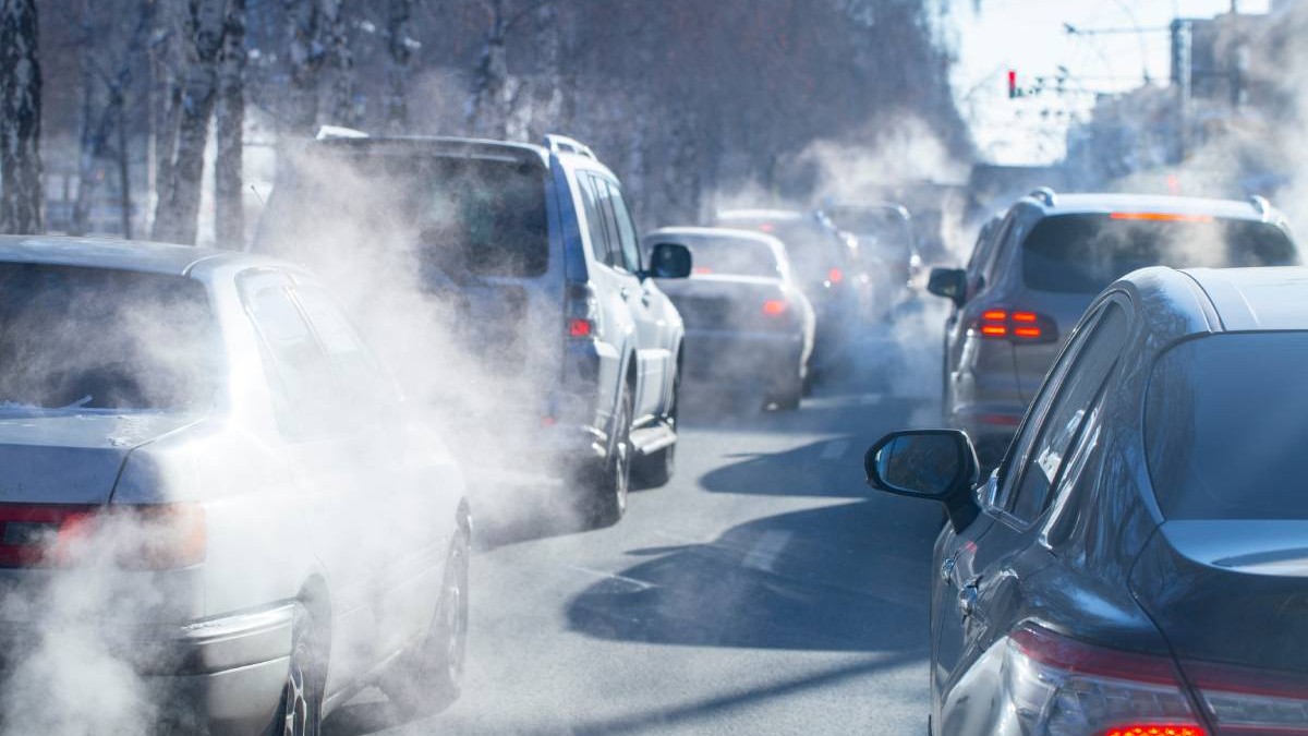 Mașini vechi, blocate în aglomerația din trafic în timp ce se vede și fumul gazelor de eșapament.