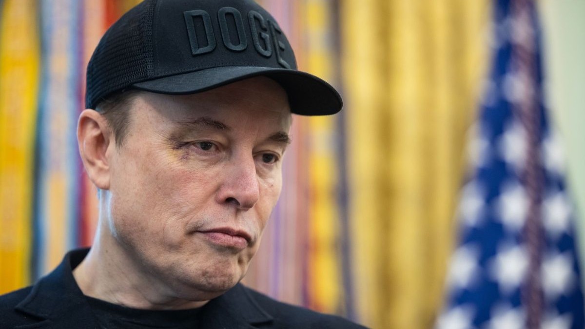 Elon musk, cu un ochi vânăt , sapcă neagră pe cap inscriptionată cu DOGE si o bluza tot neagră