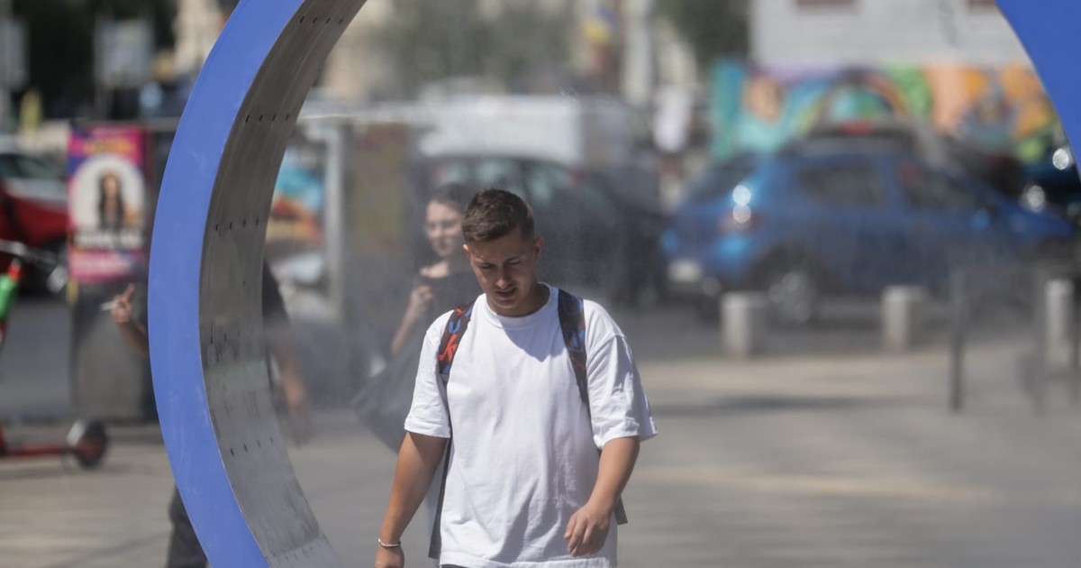 Un bărbat merge printr-o stație de răcorire instalată în București, îmbrăcat în tricou alb.
