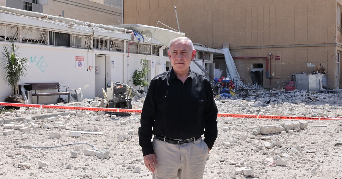 Benjamin Netanyahu surprins cu o mână în buzunar, în timpul vizitei la spitalul Soroka atacat de Iran, pe 19 iunie 2025. Premierul poartă o cămașă neagră și o pereche de pantaloni crem