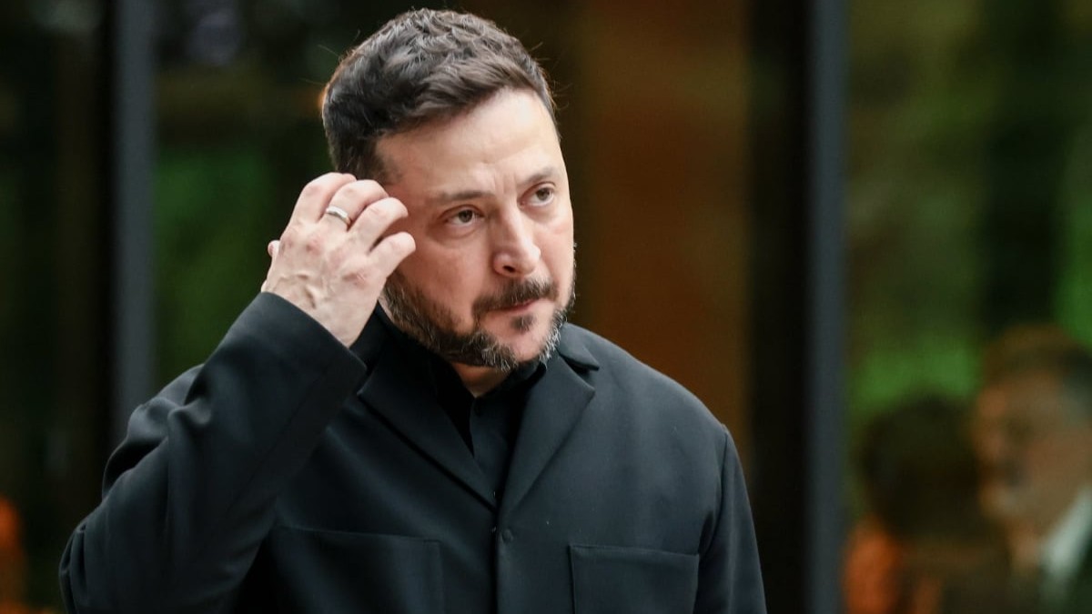 Președintele ucrainean Volodimir Zelenski, în timpul unui eveniment, este îmbrăcat în gru și se scarpină cu mâna la tâmplă