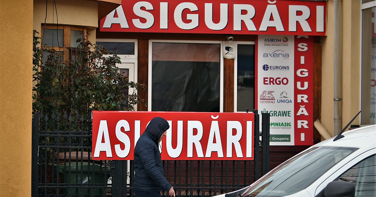 Oameni trecând prin fața unui magazin pe care scrie mare Asigurări