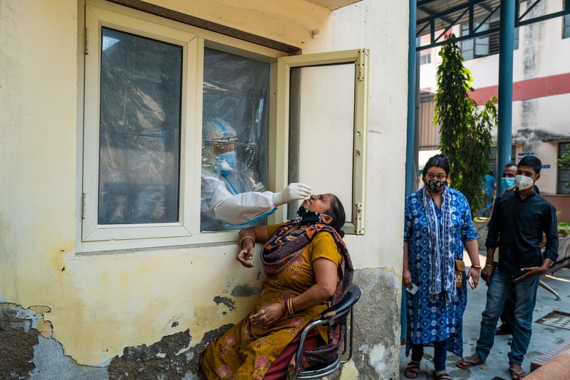 Un medic ia probele pentru testele COVID de la fereastra clinicii, în New Delhi. Foto: Profimedia