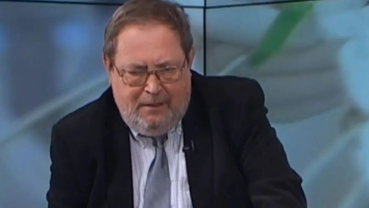 Dr. ortoped Ovidiu Alexa, îmbrăcat într-un sacou negru, cu o cămașă albă și cravată gri, stând ușor aplecat în față
