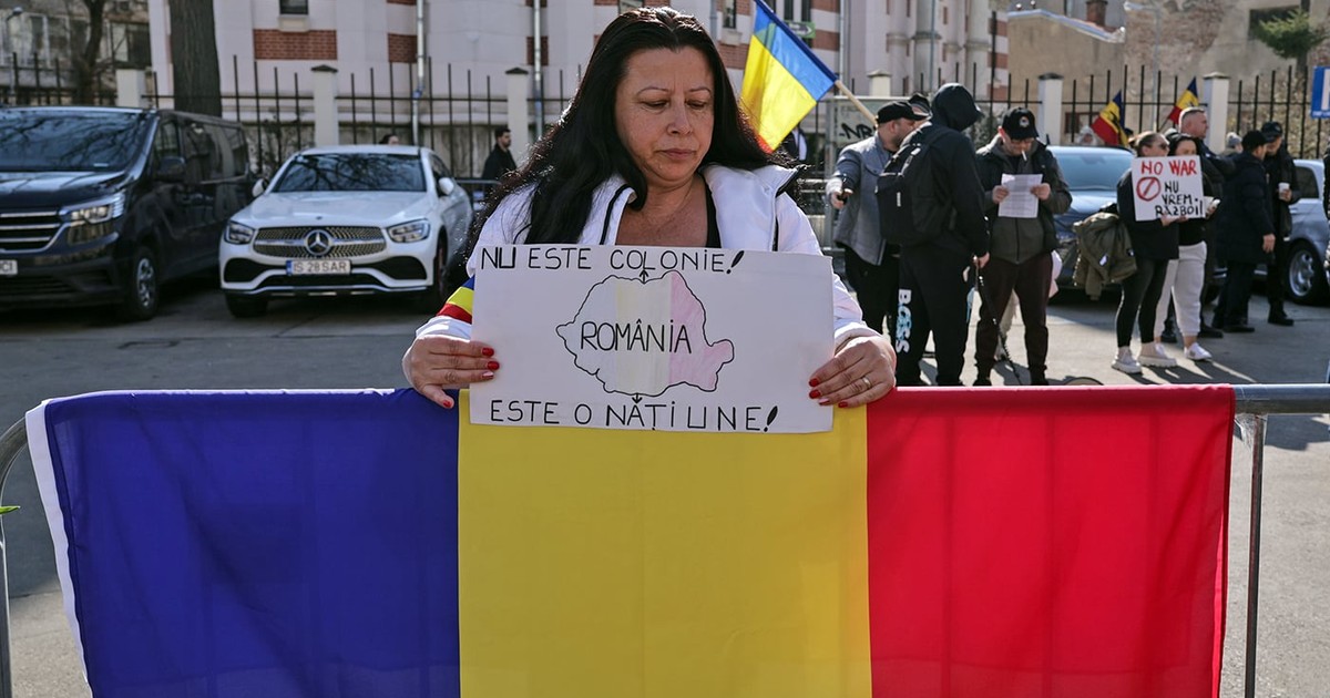 O femeie protesteaza cu un steag al Romaniei si o pancarta