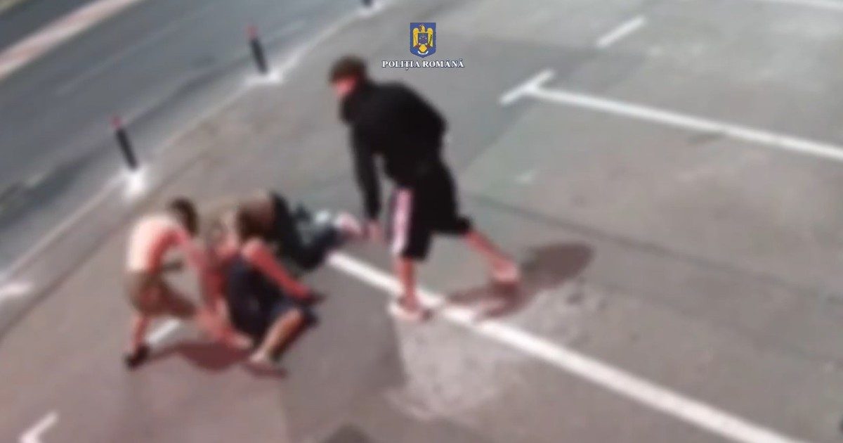 Imagine de pe o cameră de supraveghere, blurată, în care apar trei tineri care îl bat pe un bărbat căzut pe stradă