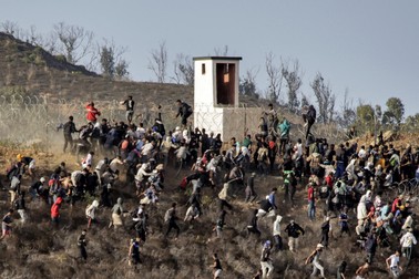 Migrants storm a barbed-wire fence as they attempt to cross the land border with Spain's African enclave of Ceuta near Fnideq in northern Morocco on September 15, 2024.,Image: 907992977, License: Rights-managed, Restrictions: , Model Release: no