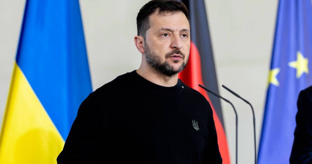 Volodimir Zelenski, îmbrăcat în negru, ține un discurs, iar în spatele său este așezat steagul Ucrainei și steagul Uniunii Europene.
