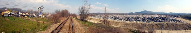 Fotografie panoramică în care se vede că groapa de gunoi (dreapta) este aproape de casele oamenilor