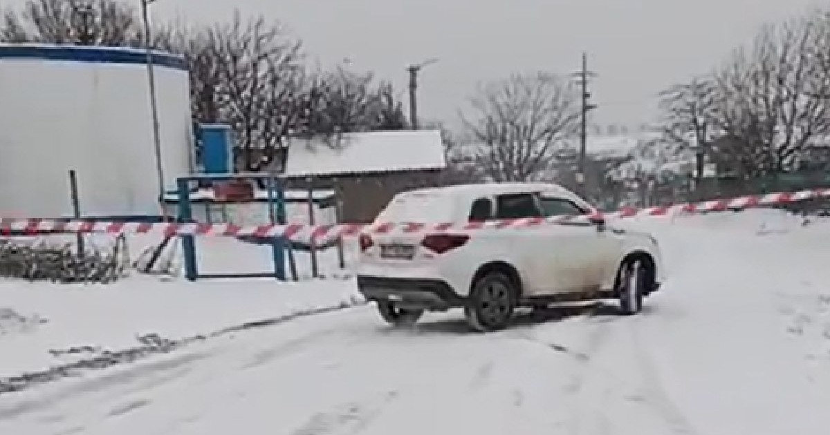 strada inchisă intr-o comună din constanta, acoperita de zapada, masina alba in fundal