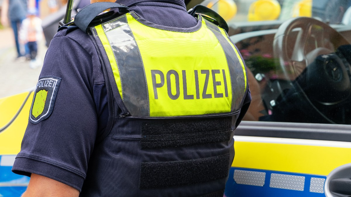 Un polițist german, lângă o mașină de poliție, în timp ce scrie o amendă