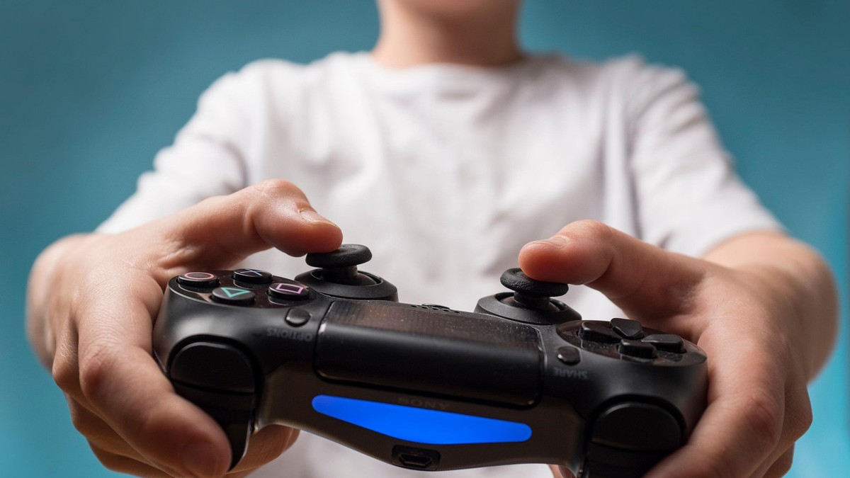 Copil care ține în mâini un controller Playstation.